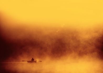 Lone fisher boat floating in foggy morning warm red yel ... 