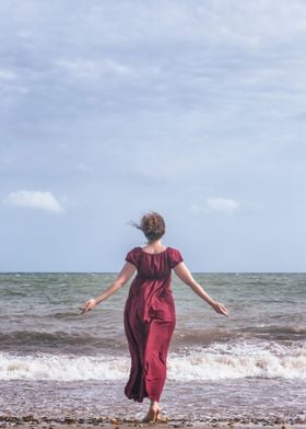 a woman in a red dress is walking into the sea