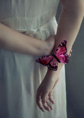 Pink butterfly resting on the arm of a girl