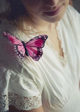 Pink butterfly resting on the shoulder of a girl