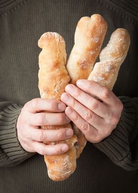 Man holding three rustic artisan French baguettes