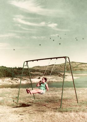 Single young girl bouncing in a swing near a lake