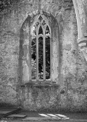 An old abbey window.  With shadow and celtic cross.