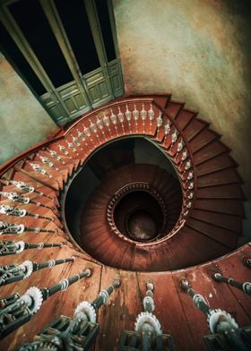 An old spiral staircase in red and brown tones. 