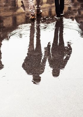 Reflection of walking couple in the puddle