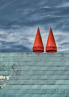 Red cones sit upon a blue wall