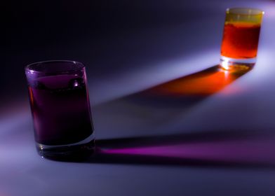 Two shot glasses with orange and purple liquids in them ... 