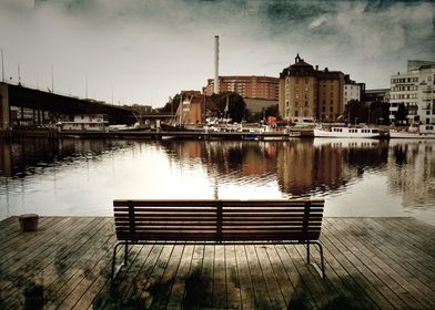 Textured image of bench by the water in the city.