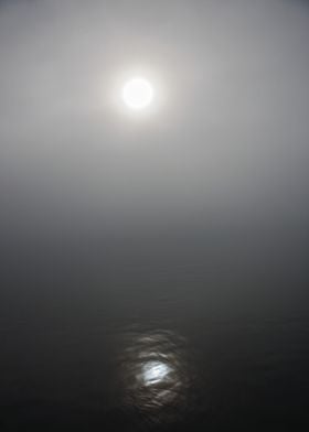 The sun peeking through the fog. 