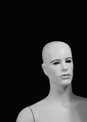 A bald, black and white manikin / mannequin against a b ... 