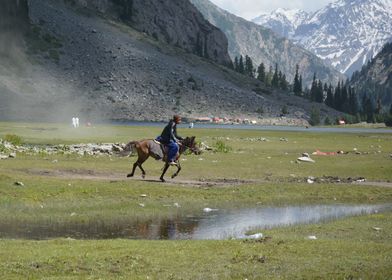 Horse riding beside lake.
