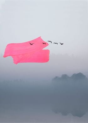 Birds fly over misty lake