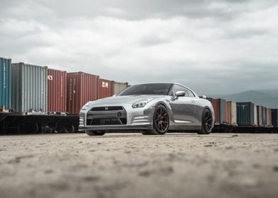 Silver Nissan GTR R35 next to freight train cars 