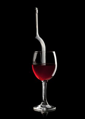 Elegant photo of a wine bottle and wine glass with red wine on a black background. The glass is in front of the bottle and has a rich intense red color. Bottle silhouette is made by the light reflection. Sophisticated composition for wine lovers.