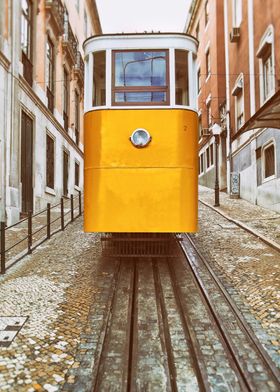 Elevador da Gloria Funicular, Lisbon, Portugal. Iconic yellow tram or streetcar which connects Restauradores Square to Bairro Alto, the famous district known for its night life. The tram is positioned on a set of tracks rails with a steep street behind.