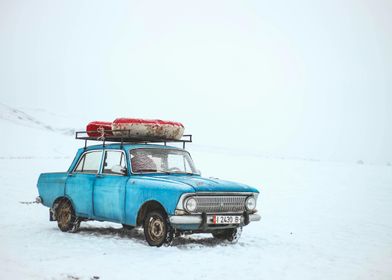 Blue Car in Snowy Landscape