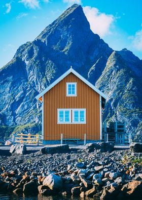 Nordic serenity: A cozy cabin framed by the majestic Olstinden near Reine.